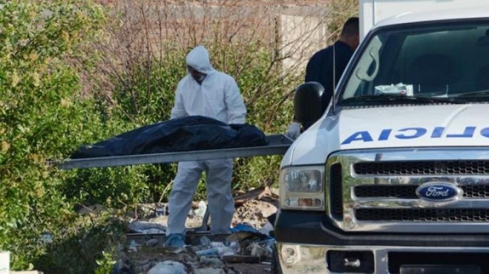 Los peritos retiran uno de los cuerpos de las mujeres asesinadas en la ciudad de Monte Quemado.