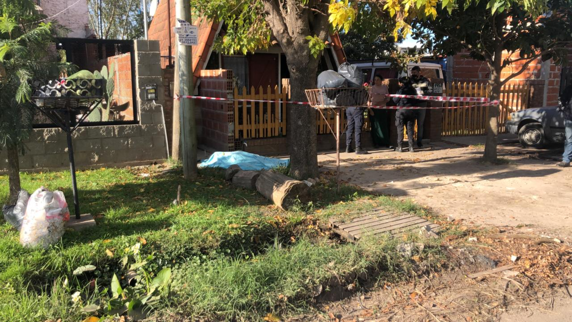 El cadáver de Florencia Sandoval yace, cubierto, en la vereda de la vivienda familiar.