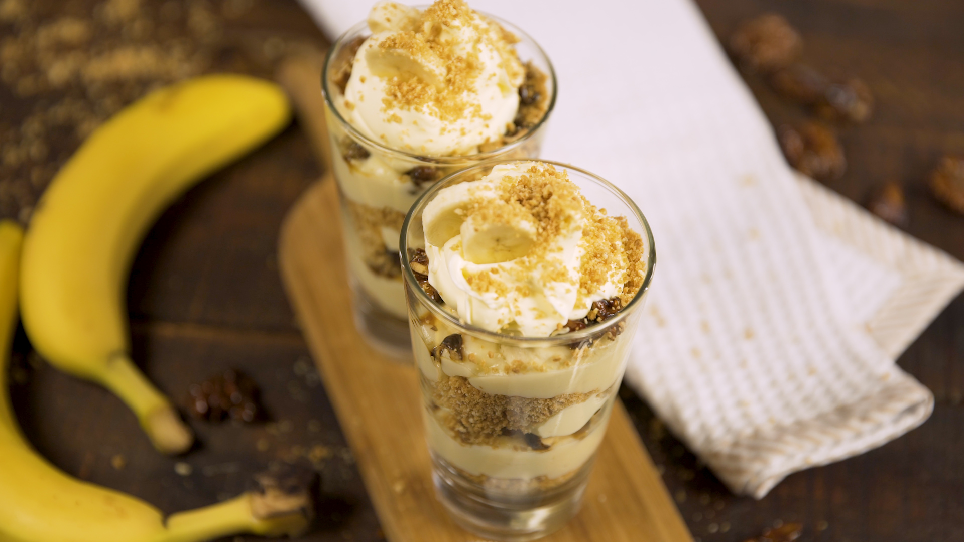 Copa hecha a base de banana, nueces con caramelo, galletitas trituradas y crema batida.