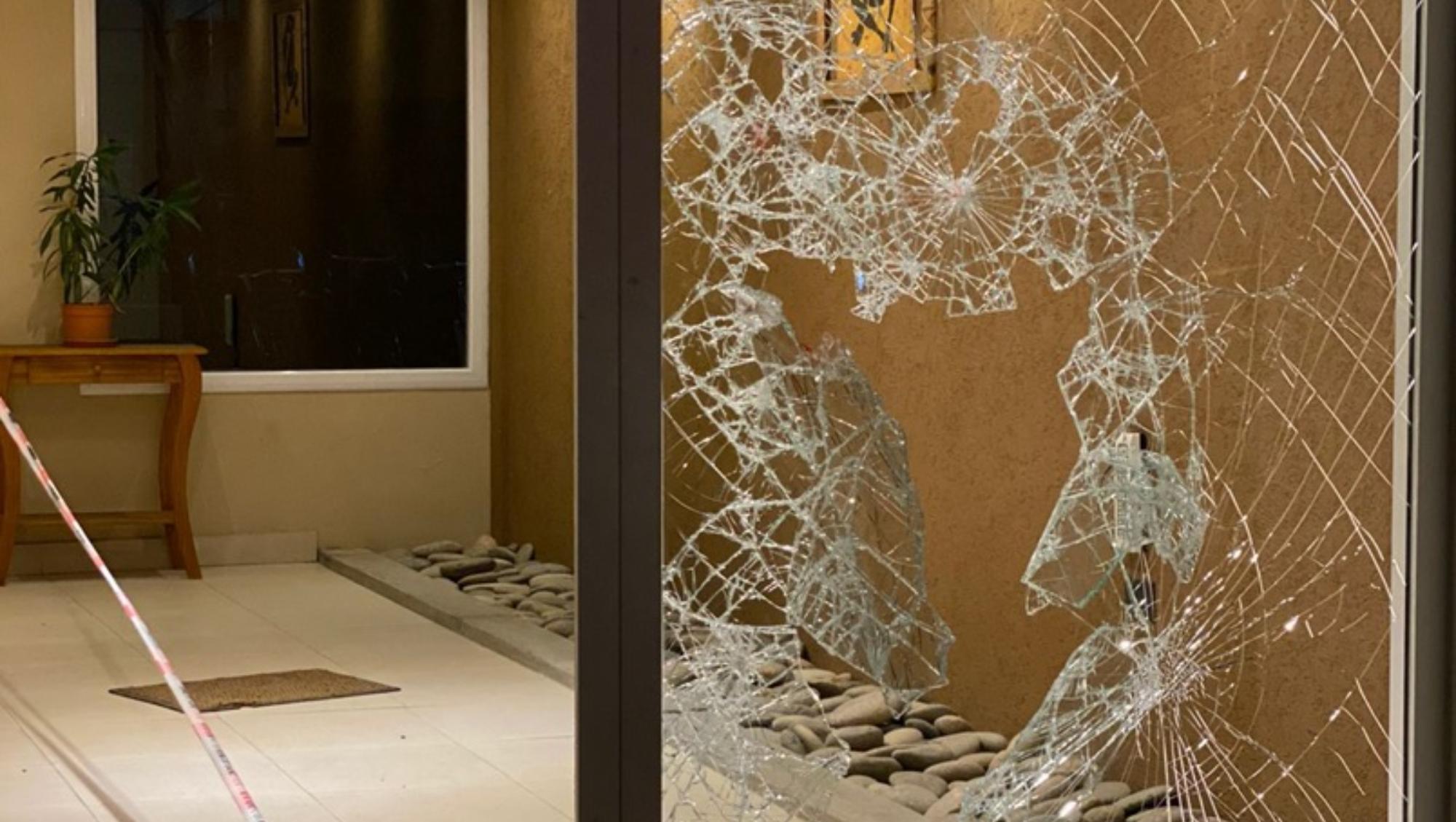 El cristal de la puerta del edificio fue destrozado a balazos por el imputado.