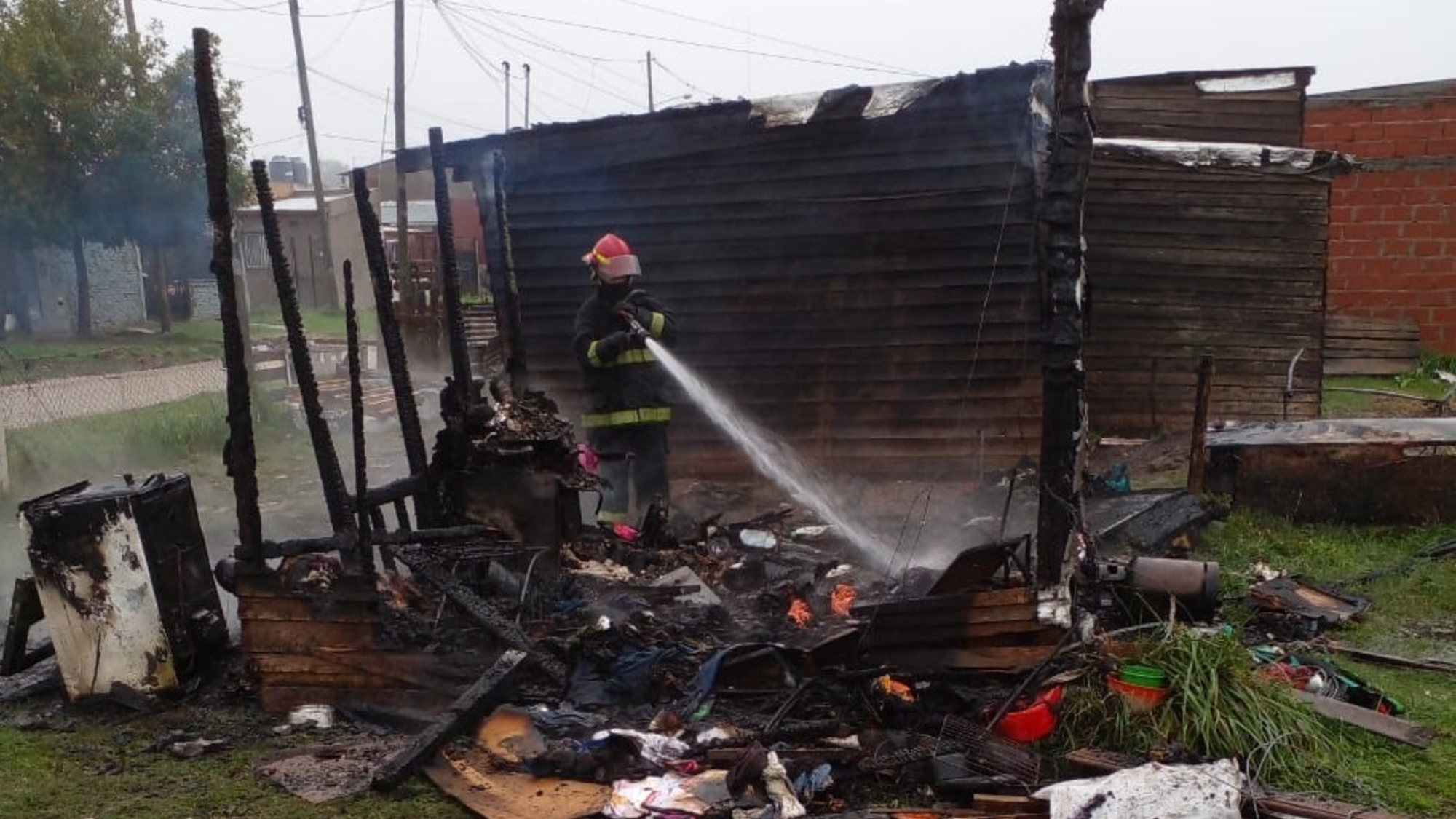 Los bomberos terminado de apagar el fuego de la precaria vivienda.