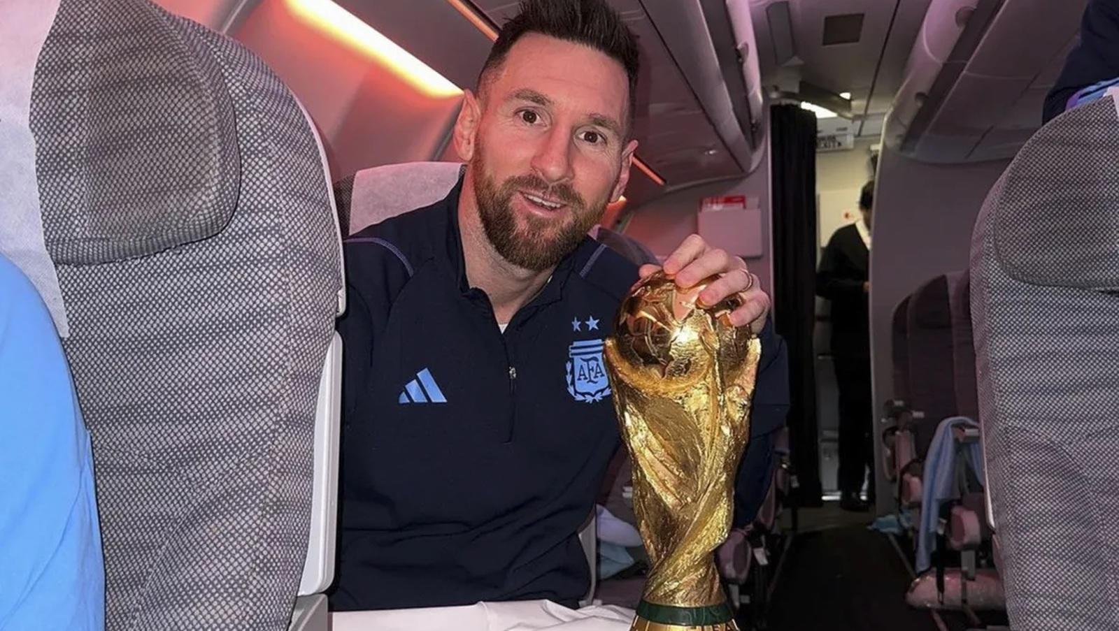 Lionel Messi posando con el trofeo logrado en el Mundial Qatar 2022 en el vuelo de regresó que traerá a la Selección a Argentina (Gentileza @leomessi/Instagram).