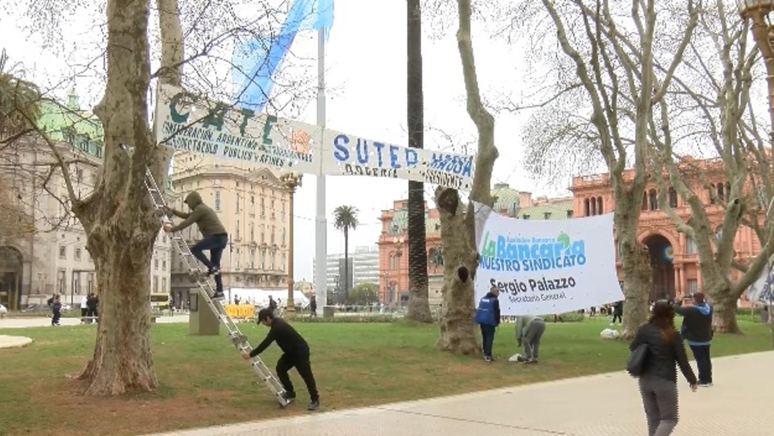 Los primeros manifestantes y sus banderas en Plaza de Mayo (Captura de pantalla-Gentileza Télam).